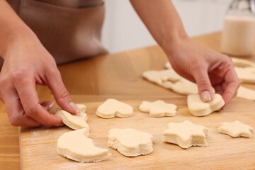 Woman with raw cookies at wooden table, closeup
