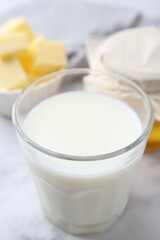 Fresh milk in glass, honey and butter on white marble table, closeup