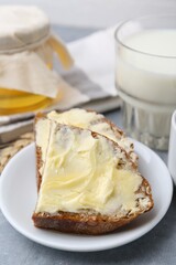 Slices of bread with butter, honey and milk on light grey table, closeup