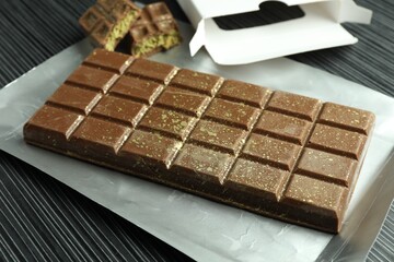 One tasty Dubai chocolate bar with pistachios and knafeh on black wooden table, closeup