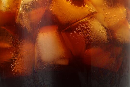 Refreshing coffee with ice cubes as background, closeup