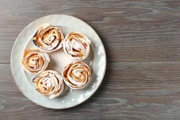 Freshly baked apple roses on wooden table, top view. Space for text