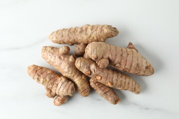 Raw turmeric roots on white marble table, top view