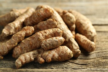 Pile of tumeric rhizomes on wooden table, closeup