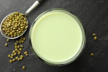 Fresh mung bean juice in glass and seeds on black table, flat lay