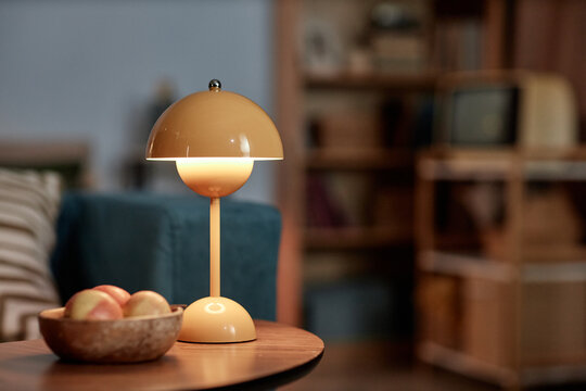 Still life shot of lit lamp glowing with warm comforting light placed on tea table in living room, copy space