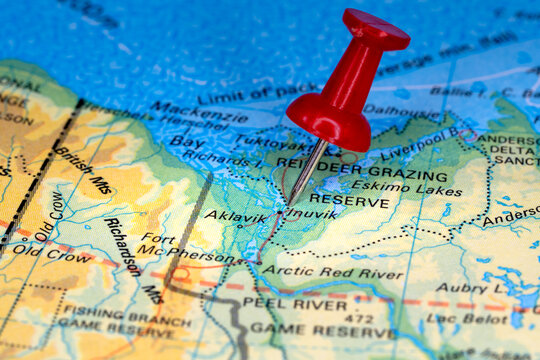 Tourist map of Northwest Territories with a red pin stuck in next to Inuvik. Colorful map
