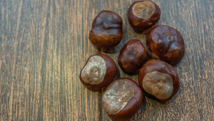 A bunch of chestnuts rests on a smooth, homogeneous background, highlighting their rich, glossy shells. Perfect for showcasing seasonal flavors or healthy snacking. Space available for text.