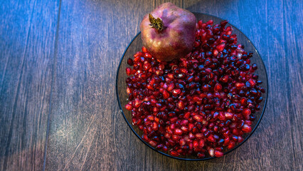 A bowl filled with vibrant, peeled pomegranate seeds alongside a whole pomegranate. The juicy arils glisten, showcasing their rich color and texture, perfect for healthy snacks or recipes.