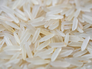 Close-up shot of dry, uncooked long grain basmati rice. Grains are slender and translucent, natural texture.