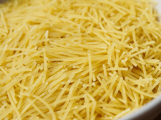 Close-up of small, thin vermicelli filini pasta. Delicate strands create a fine, textured food background.