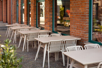 Outdoor street cafe tables ready for service. Empty cafe terrace with table and plastic chair, morning time. Food concept