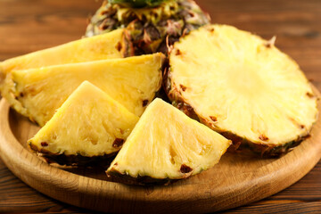 Cut fresh ripe pineapple on wooden table, closeup
