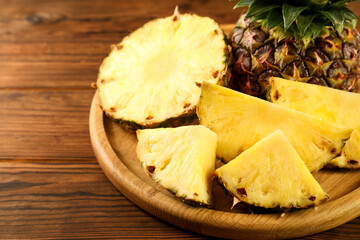 Cut fresh ripe pineapple on wooden table, closeup
