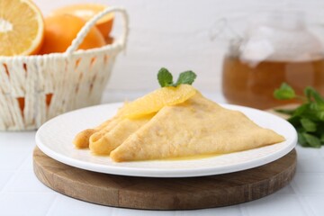 Tasty crepes Suzette on white tiled table, closeup