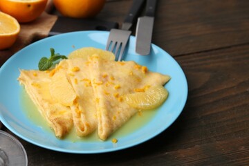 Plate with tasty crepes Suzette on wooden table, closeup