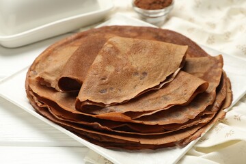 Delicious chocolate crepes on white wooden table, closeup