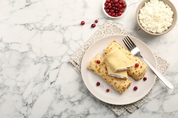 Delicious rolled crepes with cottage cheese, raisins and cranberries on white marble table, flat lay. Space for text