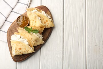 Delicious crepes with cottage cheese, jam and mint on white wooden table, top view. Space for text