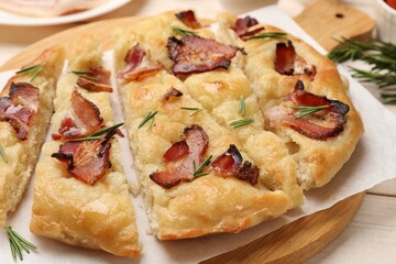 Slices of delicious focaccia bread with bacon and rosemary on table, closeup