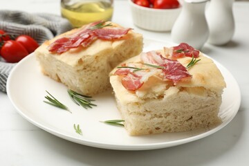 Pieces of delicious focaccia bread with bacon served on white table, closeup
