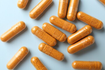 Turmeric capsules on light blue background, flat lay