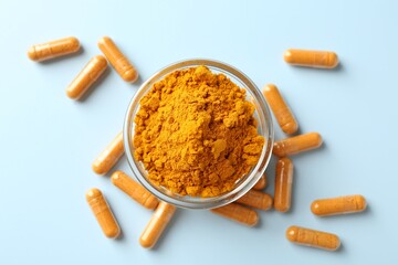 Turmeric capsules and powder on light blue background, flat lay