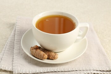 Aromatic turmeric tea and rhizomes on white textured table, closeup