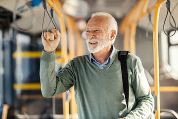 Trendy senior passenger holding handle in public transportation and riding a bus. © Dusan Petkovic