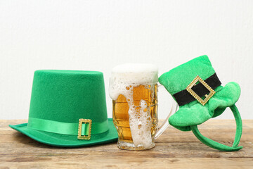 Mug of beer with leprechaun hats on wooden table against white background. St. Patrick's Day...