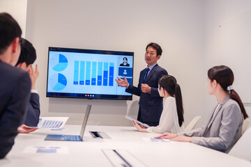 会議で資料を見ながらプレゼンをする中年のオフィスワーカー
