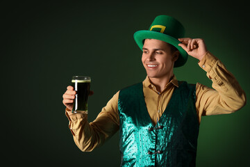 Happy young man with beer on dark green background. St. Patrick's Day