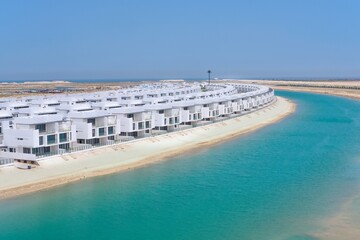 Panoramic view on new waterfront villas neighborhood with direct access to beach on completion stage. Luxury villas residential community under construction. Modern middle eastern urban architecture