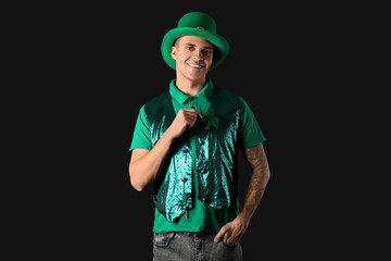 Young man in green clothes on dark background. St. Patrick's Day