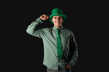 Happy young man in green leprechaun's hat on dark background. St. Patrick's Day