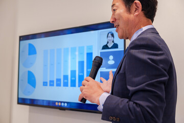 会議で資料を見ながらプレゼンをする中年のオフィスワーカー