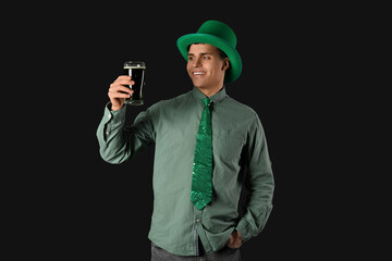 Happy young man in green hat and with beer on dark background. St. Patrick's Day