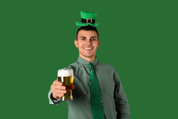 Happy young man with beer on green background. St. Patrick's Day
