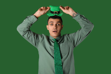 Surprised young man on green background. St. Patrick's Day