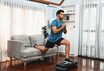 Athletic and sporty man doing squat during home body workout exercise session for fit physique and...