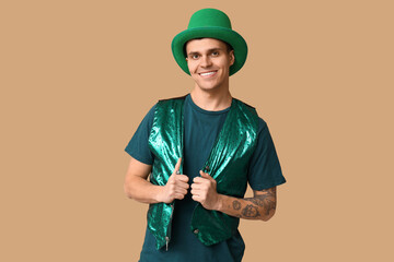 Happy tattooed young man in green clothes on beige background. St. Patrick's Day