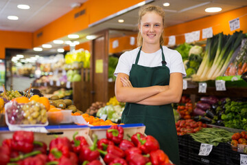 Portrait of young smiling woman worker seller in a vegetable section supermarket standing at work...