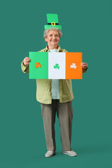 Happy senior woman in leprechaun hat with paper Irish flag for St. Patrick's Day celebration on...