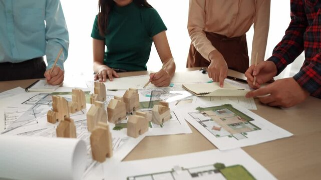 Smart architect and safety engineer discussion about building blueprint on table with architectural document, measurement tools and wooden block scatter around at modern office. Closeup. Delineation.