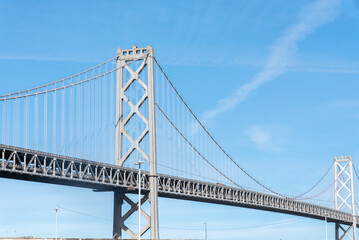 A large bridge spans a body of water, with a clear blue sky above