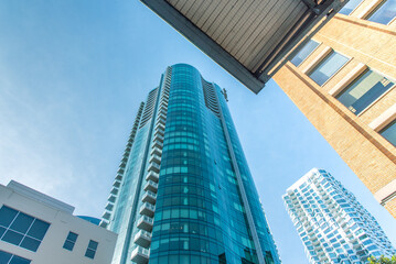 A tall building with a glass facade is seen from below