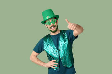 Young man in leprechaun hat and decorative glasses in shape of clover with green beard showing...