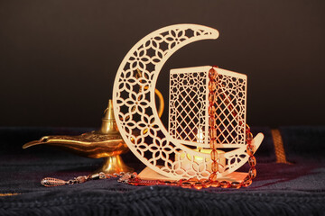 Blue mat with decorative crescent, burning candle, prayer beads and Aladdin lamp for Ramadan on...
