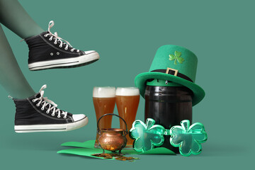 Female legs in stockings with glasses of beer, barrel and leprechaun's hat on green background. St....