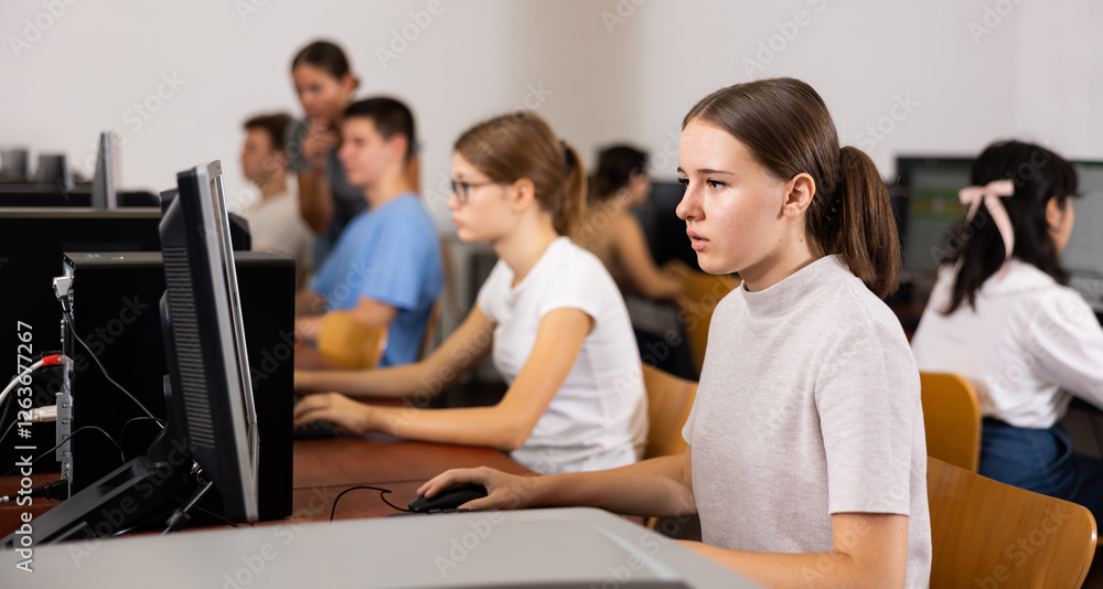 Fototapete smart female teenager learning computer science while she is using a pc in the computer classroom